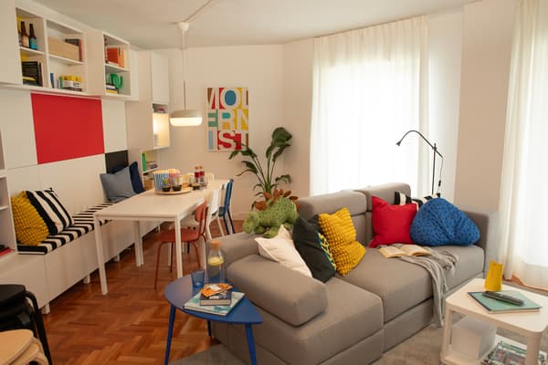 Nuevo salón con mueble para la televisión, estanterías, sofá, lámpara, mesa, accesorio y cortinas.