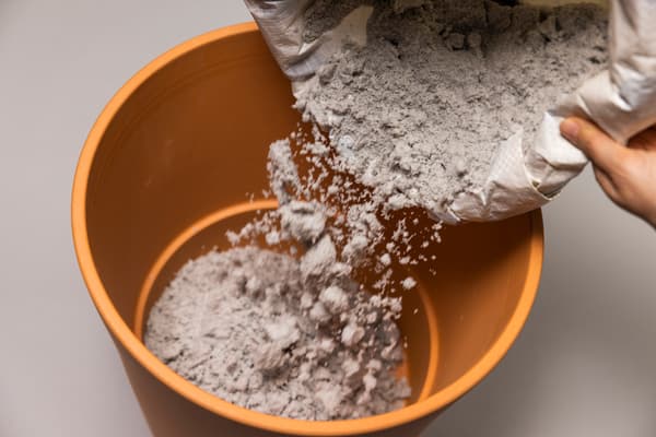Nun wird ein wenig Sand in den Tontopf gefüllt.