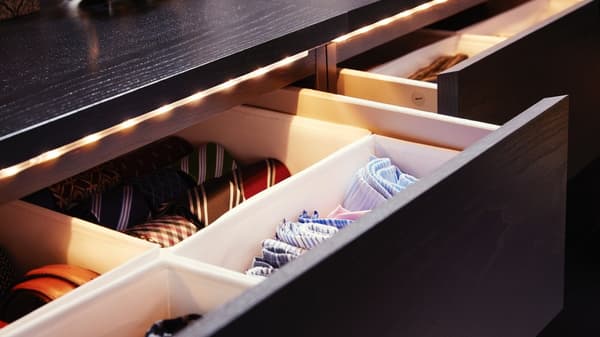 Nyitott fiók rekeszekkel összehajtott ingek és nyakkendők számára, LED szalagos világítással.