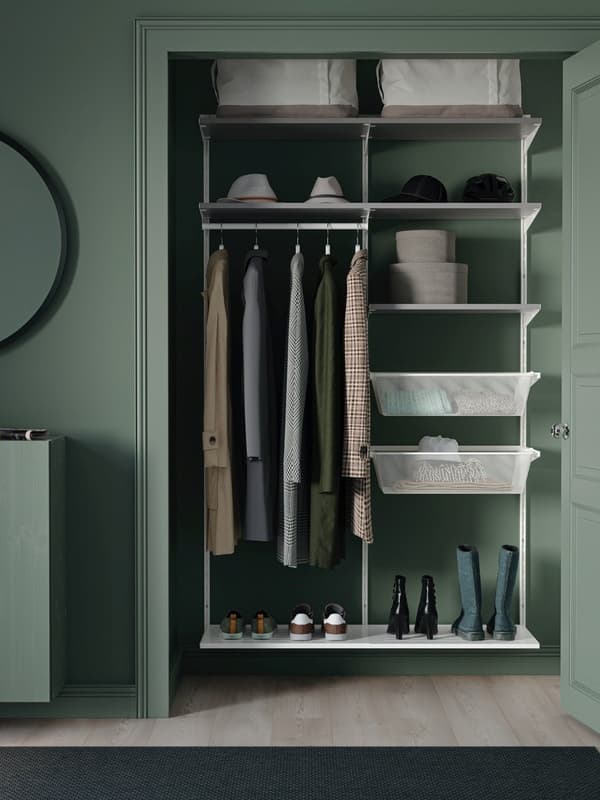 Nyitott ruhatári tér zöld belső térrel, polcokkal, kabáttartókkal, cipőkkel, kalapokkal és tárolódobozokkal.