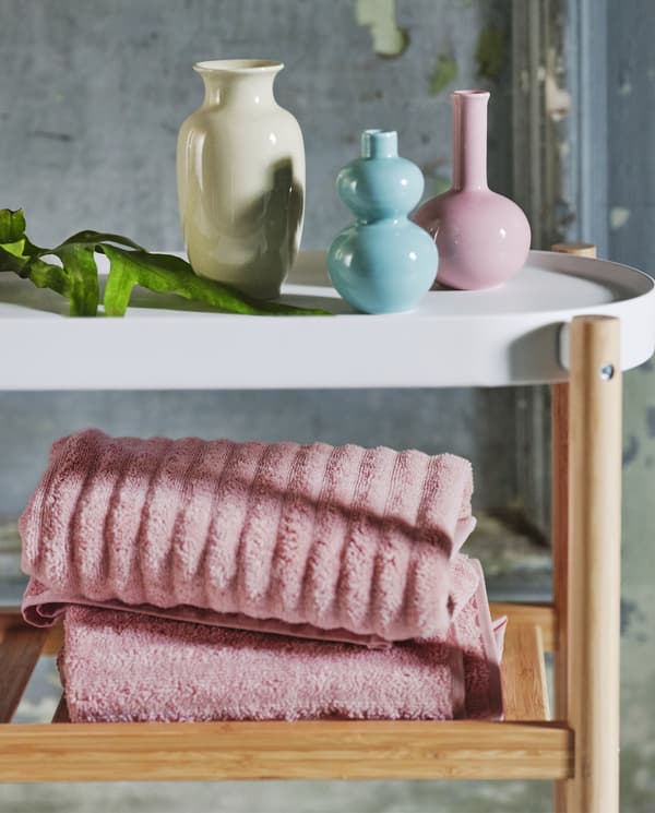 Nyitott tároló polcokkal, melyeken pasztell törülközők és vázák vannak.