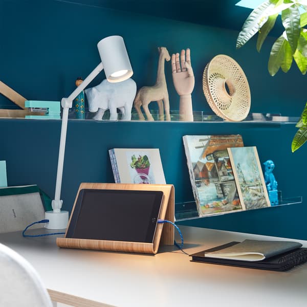 NYMÅNE work lamp illuminates a tablet on a tablet stand, and a cord from the lamp’s built-in USB port charges the tablet.