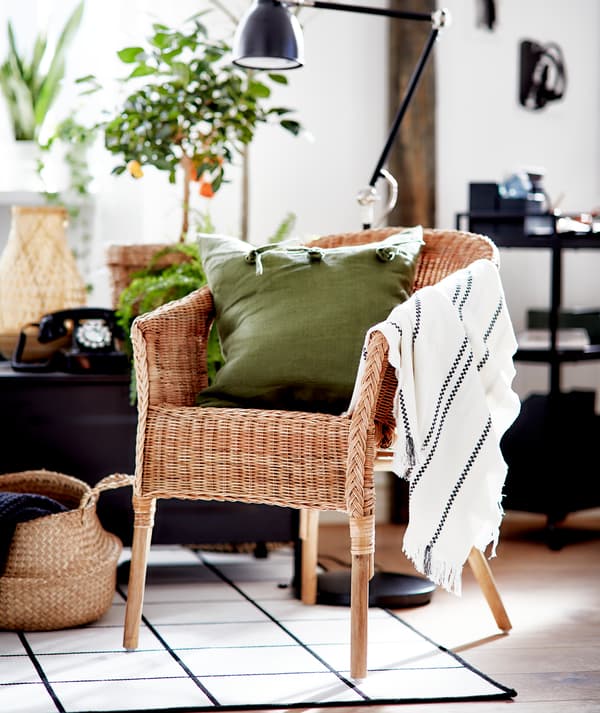 O cameră de zi cu grafică în alb și negru cu accente în materiale naturale și un scaun din ratan AGEN cu o pernă verde.