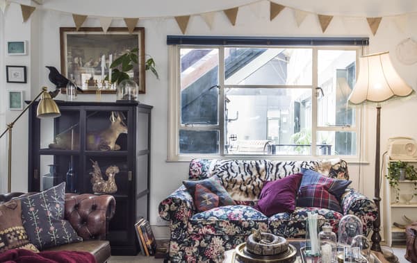 O camera de zi cu o canapea cu motive florale, vitrine și lămpi.