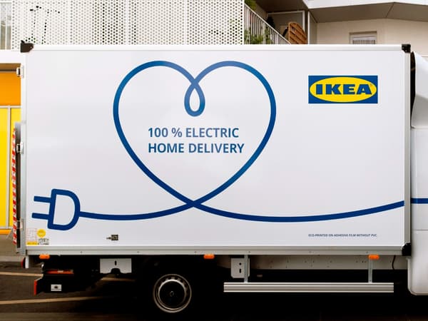 O furgonetă IKEA albă 100% electrică pentru livrări la domiciliu parcată în fața unui bloc.