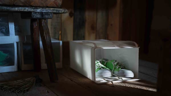 O pereche de teniși verde aprins încăpând perfect în interiorul unei cutii pantofi SKUBB.