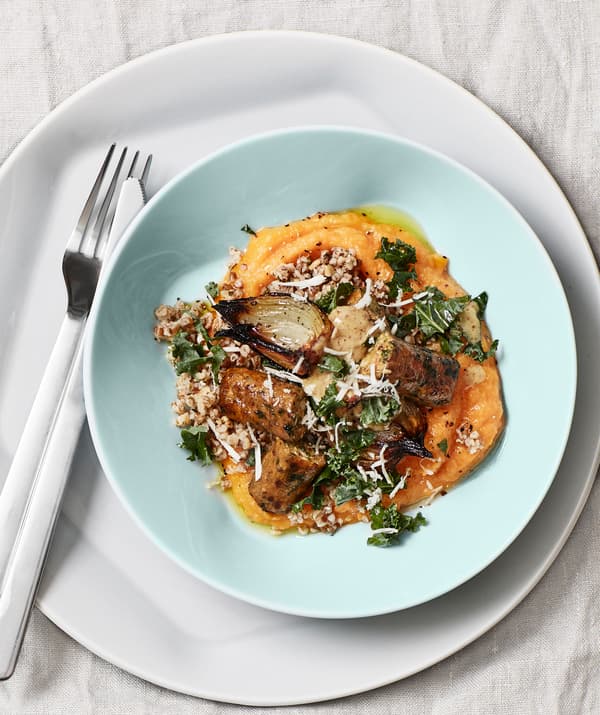 O porție colorată de mâncare într-un bol verde așezat pe o farfurie albă și tacâmuri.