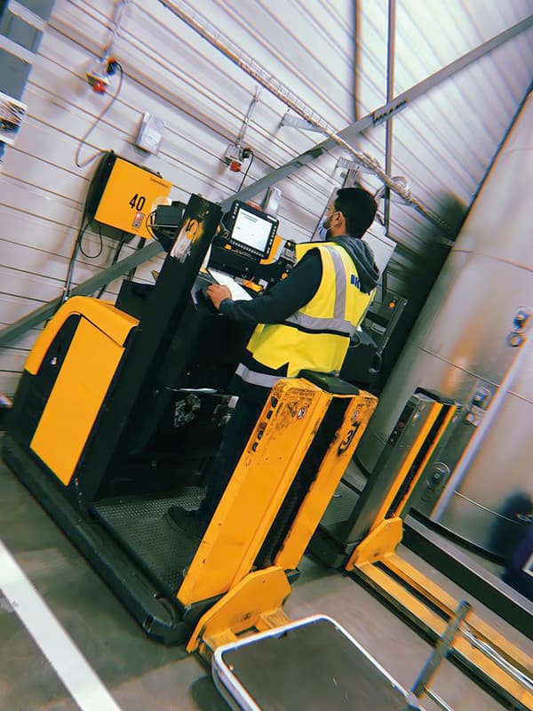 Odai, an Iraqi refugee and IKEA Switzerland co-worker, wearing a yellow vest while looking at the machine’s screen.