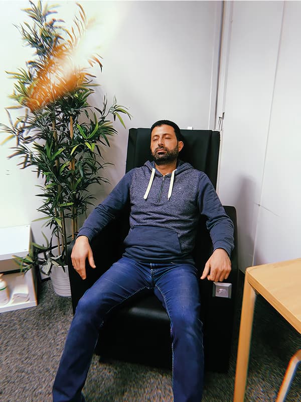Odai, réfugié irakien et collaborateur IKEA, est installé dans un fauteuil noir, vêtu d’un jeans et d’un sweat à capuche.