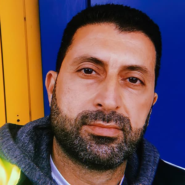 Odal, a refugee from Iraq now working for IKEA Switzerland, standing against a blue and yellow background.
