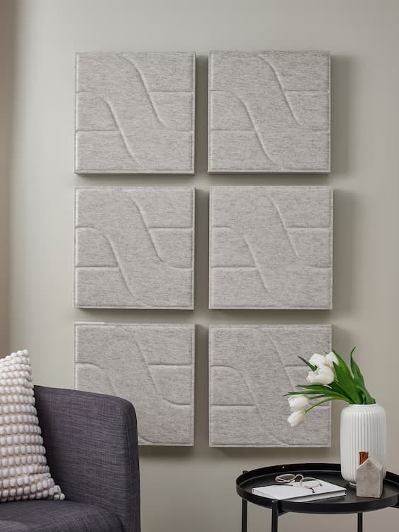 ODDLAUG sound absorbing panels hanging in a window with neutral-colored curtains in front of it.