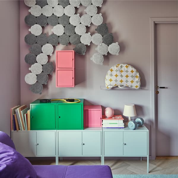 ODDLAUG sound absorbing panels in grey, on the wall of a small living space with storage cabinets and boxes, and a bed sofa.