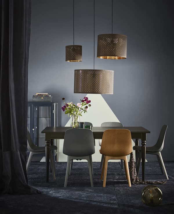 ODGER chairs, made of renewable wood and recycled plastic, set around a dining table under three pendant lamps.