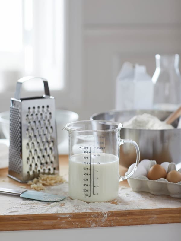 Odmerka VARDAGEN s mliekom, strúhadlo IDEALISK a misa BLANDA BLANK na pomúčenej pracovnej doske.