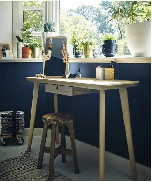 Öltözőasztal és ülőke egy kék fal előtt.