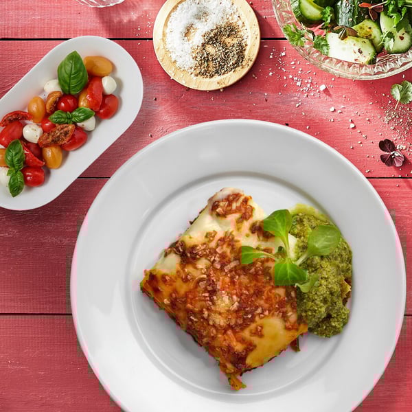 Örtig lasagne med pesto, serveras med tomat- och mozzarellasallad.