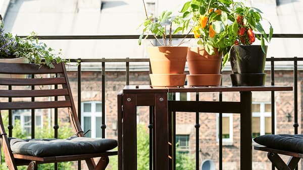 Összecsukható asztal és szék az erkélyen palántákkal.