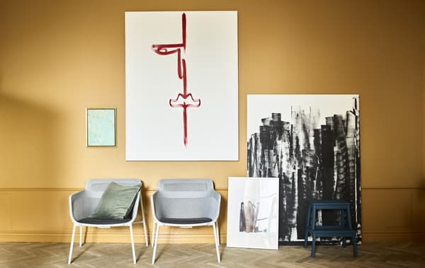 Œuvres d’art maison et deux fauteuils contre un mur ocre.
