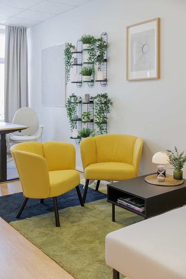 Office lounge area with yellow chairs, sofa and curtains