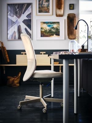 office space with a desk, a chair and lots of frames on the wall behind