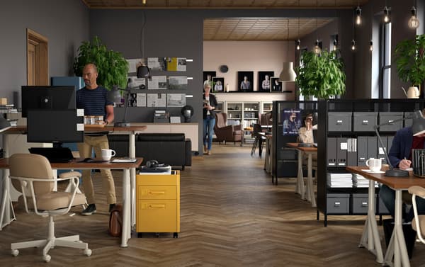 Oficina pequeña con escritorios para trabajar sentado y de pie IDÅSEN beige, sillas giratorias grises ALEFJÄLL y cajoneras marrones IDÅSEN.
