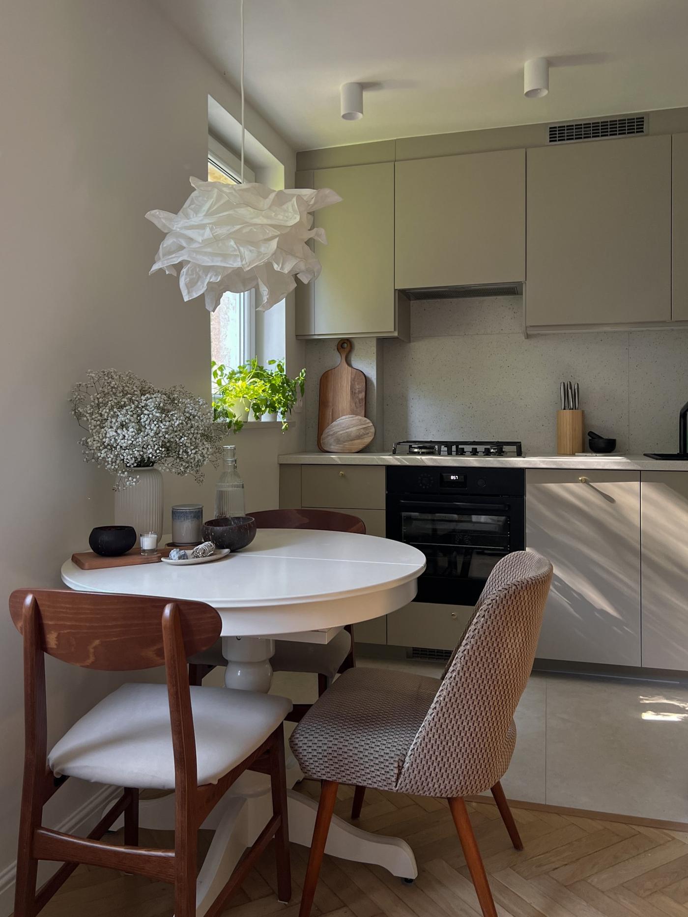 Ogrągły stół jadalniany stojący pod ścianą z kilkoma różnymi krzesłami.