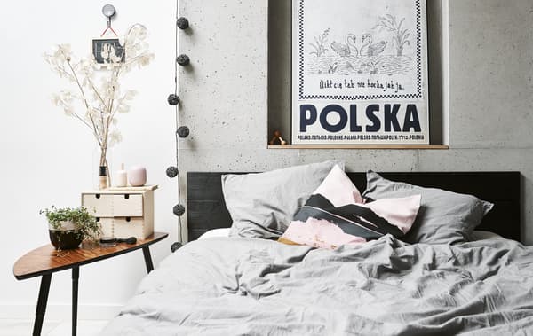 Ohe bikoitza, mahai osagarria eta oheburuko horma-hobian dagoen posterra, logela batean.