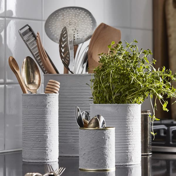 Old tins that have been painted and are now being used at utensil holders and planters