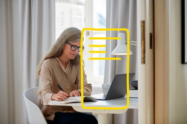 Older woman on laptop at a white desk.