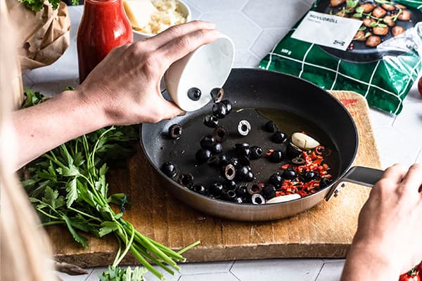 Oliven, Chili und Knoblauch werden in eine Pfanne gegeben.