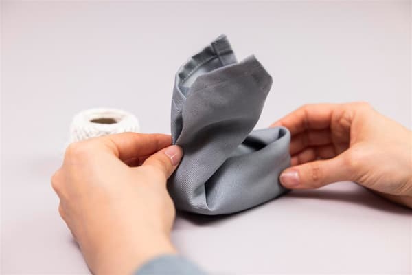 On a white plate sits a rabbit made from a napkin. The napkin has a circle at the back where you can place an egg