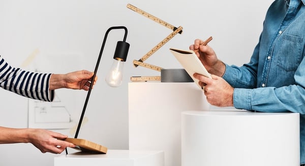 One person holding a lamp prototype others is taking notes