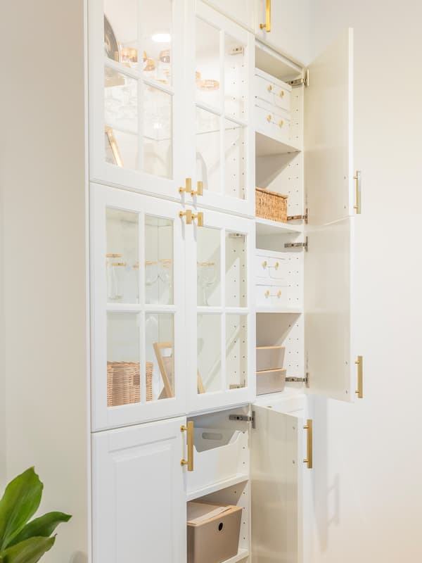 Open drawers in luxury white kitchen with marble surfaces and gold details.