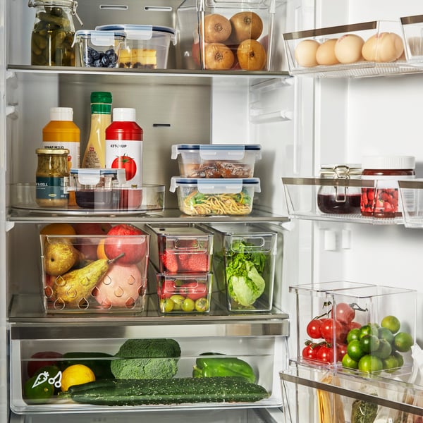Open fridge displaying a variety of fresh fruit, vegetables and condiments, neatly arranged in clear KLIPPKAKTUS storage boxes.