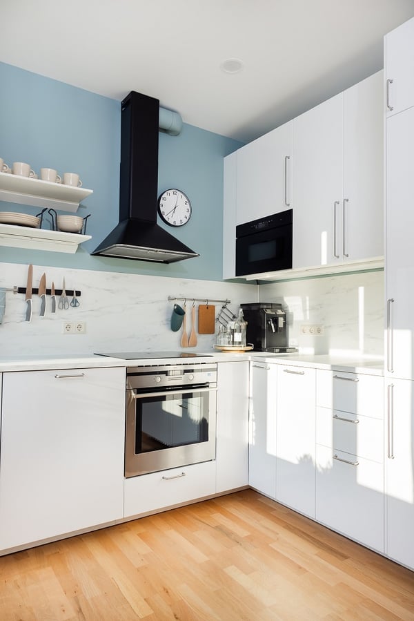 Open kitchen drawer with organized spice jars and glass containers in a modern white kitchen
