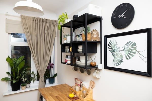Open wall shelves in a kitchen holding dishes, food items and decorative accents.