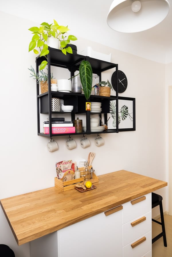 Open wall storage solution with shelves, plants and kitchen accessories.