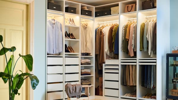 Open wardrobe system with hanging clothes shelves and drawers neatly organized with lighting