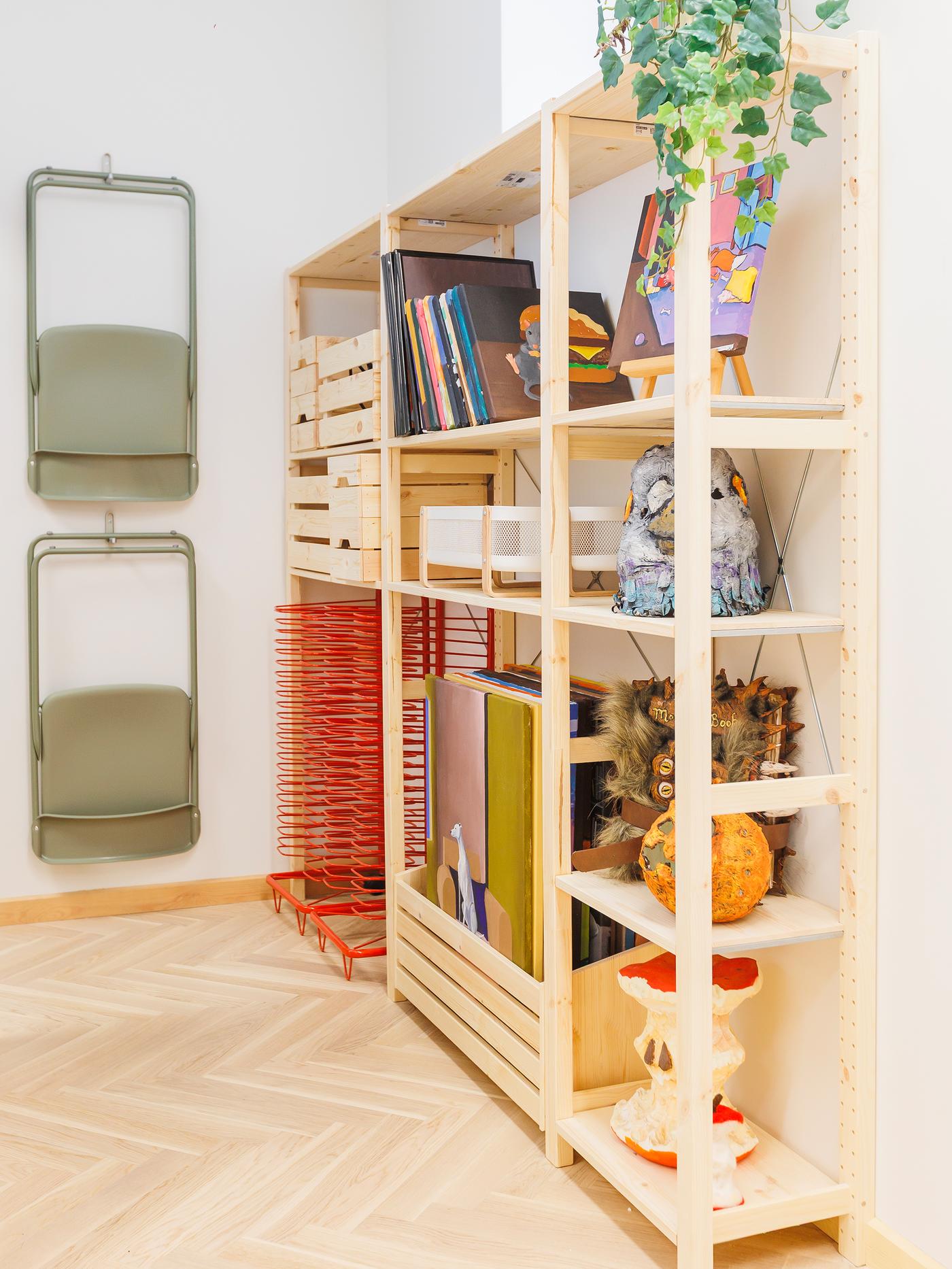 Open wooden shelving filled with books, baskets and art supplies.