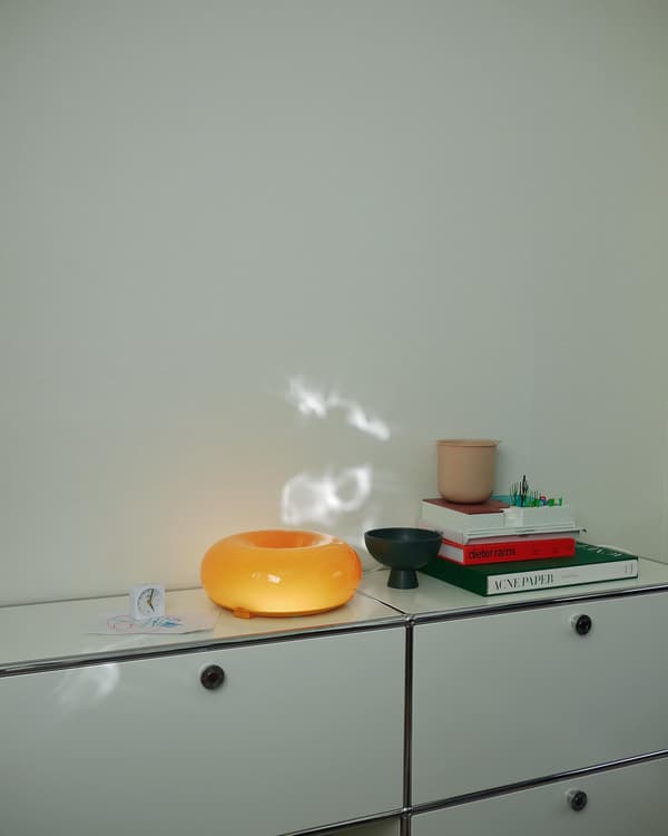 Oranssi VARMBLIXT-pöytävalaisin valkoisen lipaston päällä.