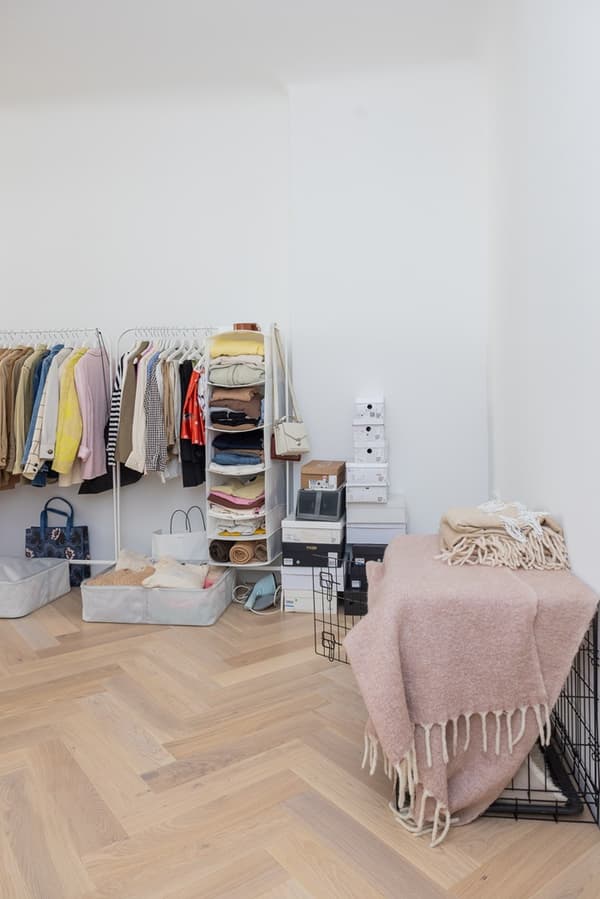 Organizēta apģērbu un aksesuāru glabāšanas sistēma ar atvilktnēm un plauktiem pie sienas.