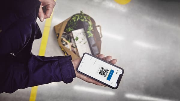 Osoba drži mobitel s prikazom QR koda i porukom.
