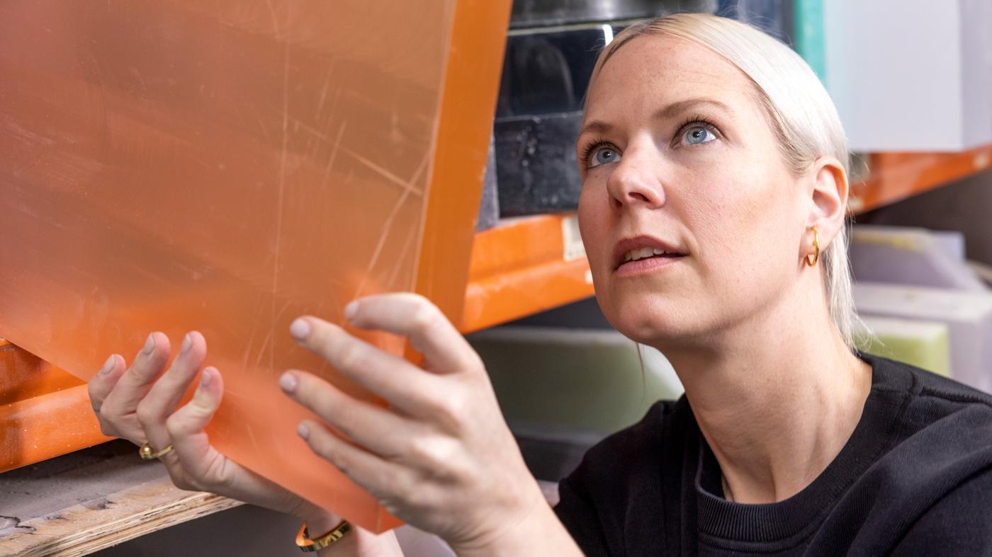 Osoba drži narančastu plastičnu ploču u skladištu