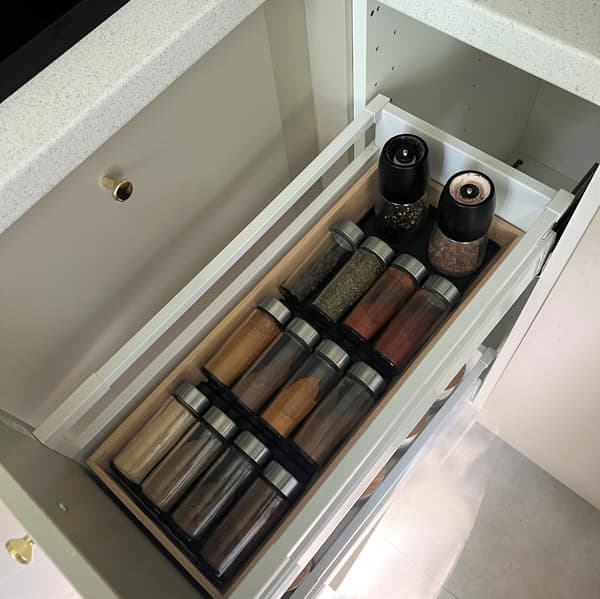 Osoba otwierająca szufladę kuchenną z przyprawami.