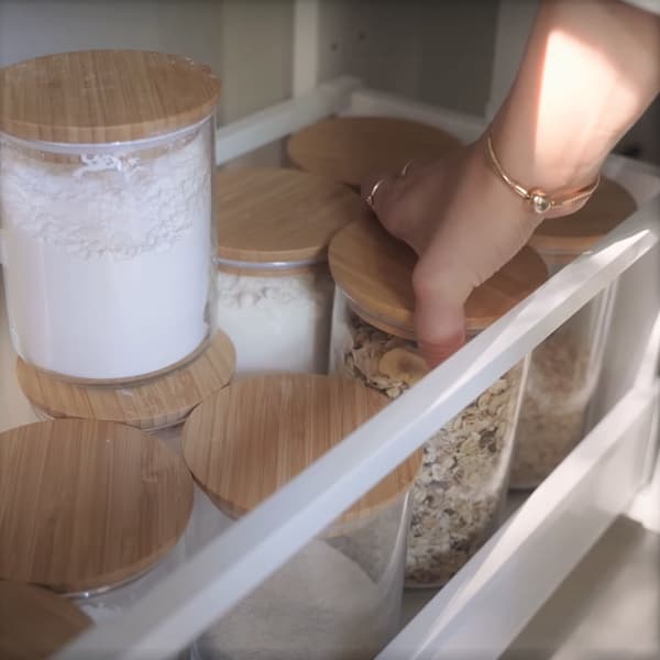 Osoba otwierająca szufladę kuchenną ze słoikami na mąki i kasze.