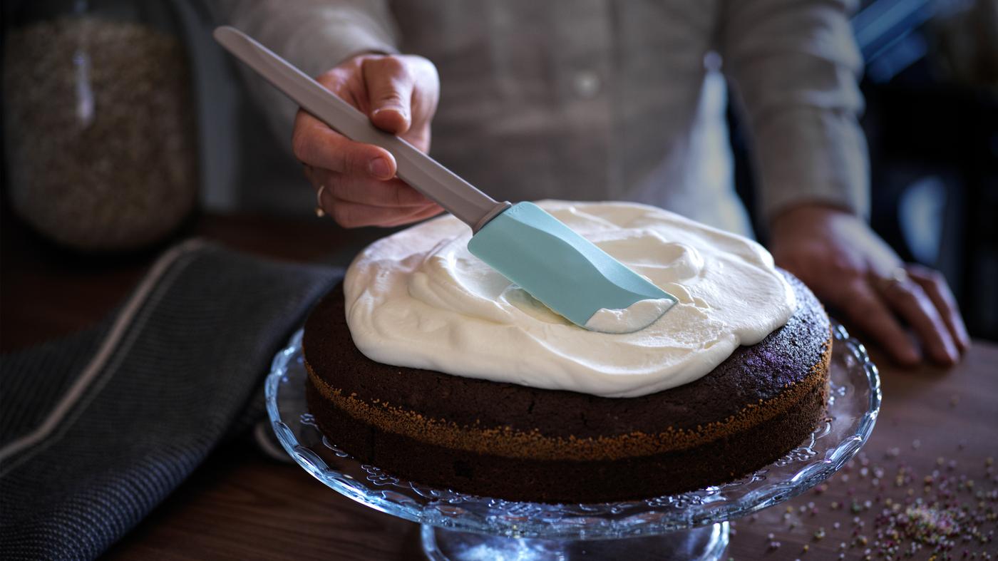 Osoba pomoću BAKGLAD spatule nanosi glazuru na tortu koja se nalazi na stalku.
