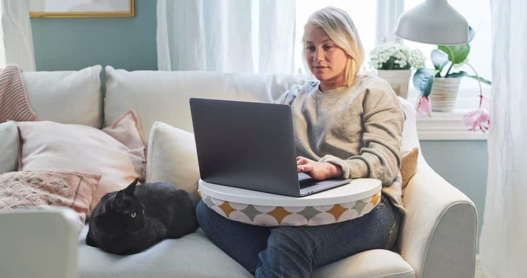 osoba pracująca na laptopie z kanapy