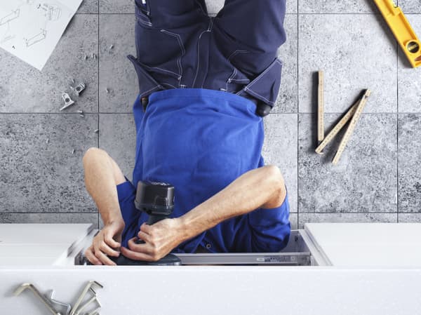 osoba pracująca na podłodze w otoczeniu narzędzi do montażu mebli