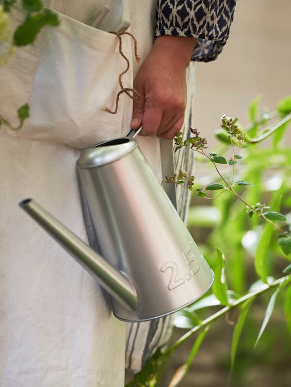 Osoba v bielej pracovnej zástere drží kanvicu ÅKERBÄR.