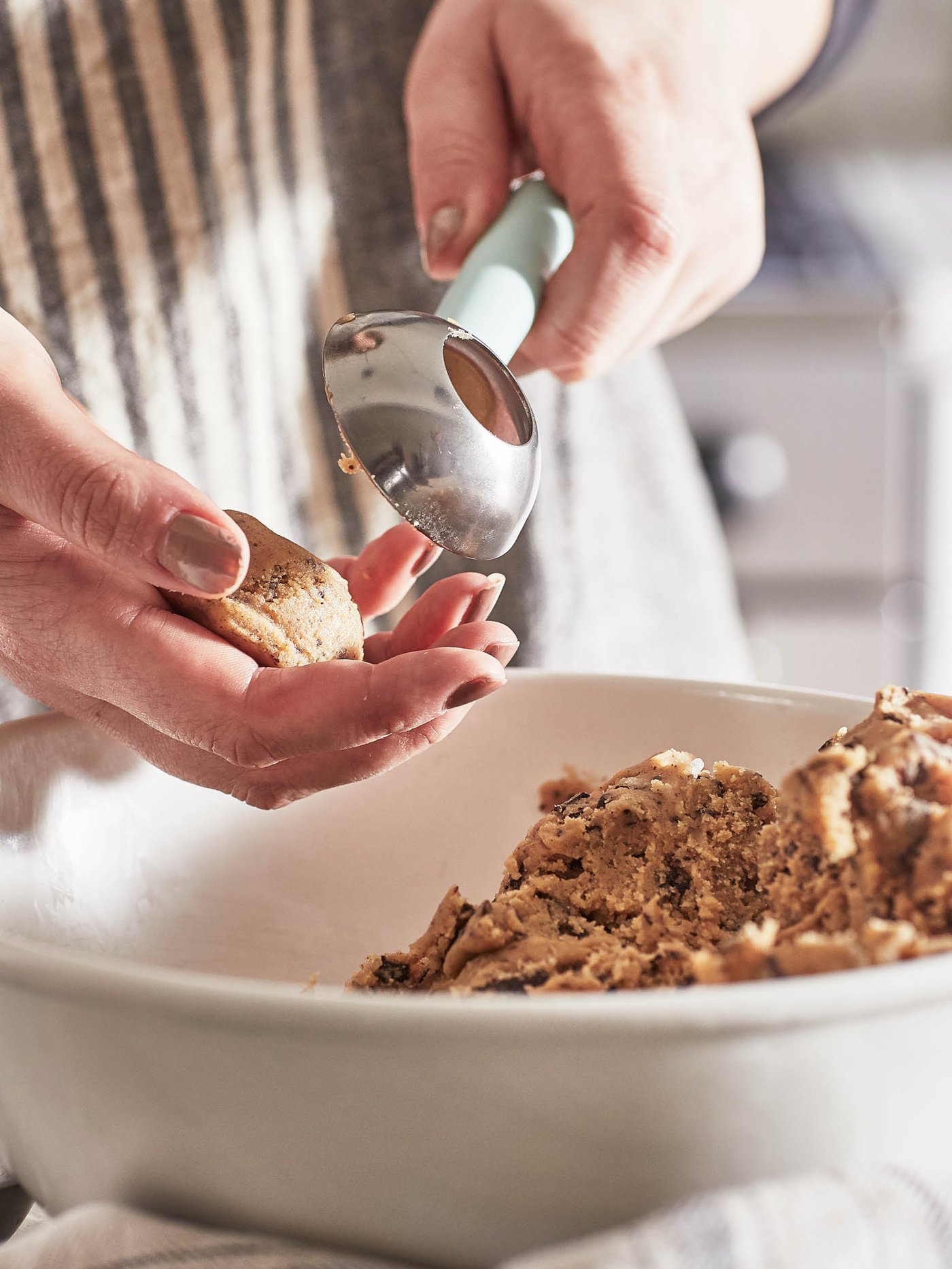 Osoba v zástere vykrajuje odmerkou LÄTTBAKAD kopčeky cesta na sušienky.